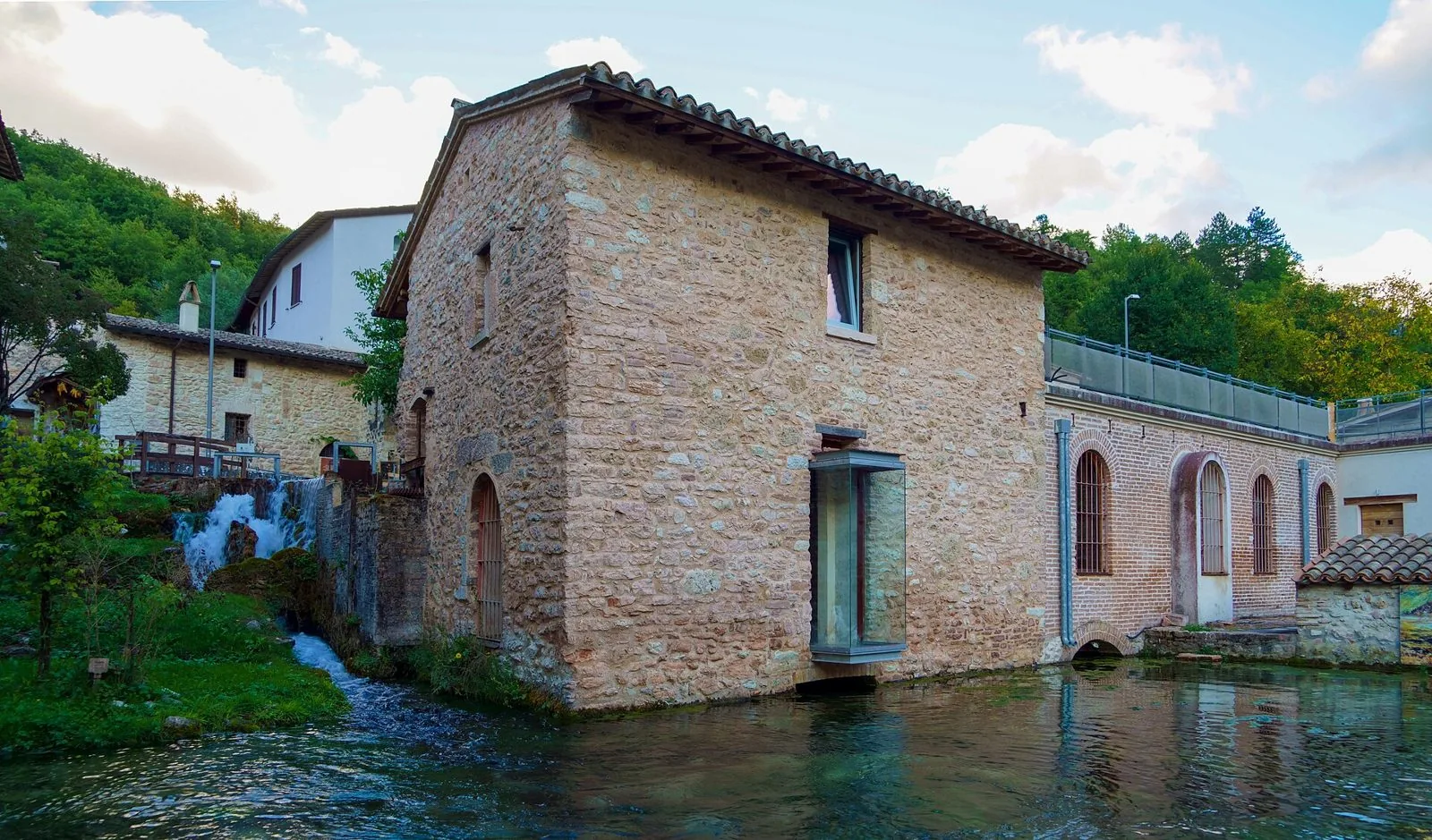 Antico mulino in pietra di Rasiglia affacciato su un bacino d'acqua limpida, con una piccola cascata