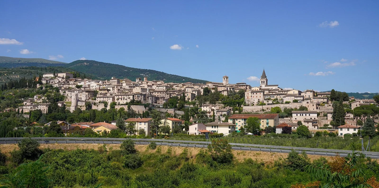 Panorama di Spello adagiato sulle pendici del monte Subasio sotto un cielo azzurro
