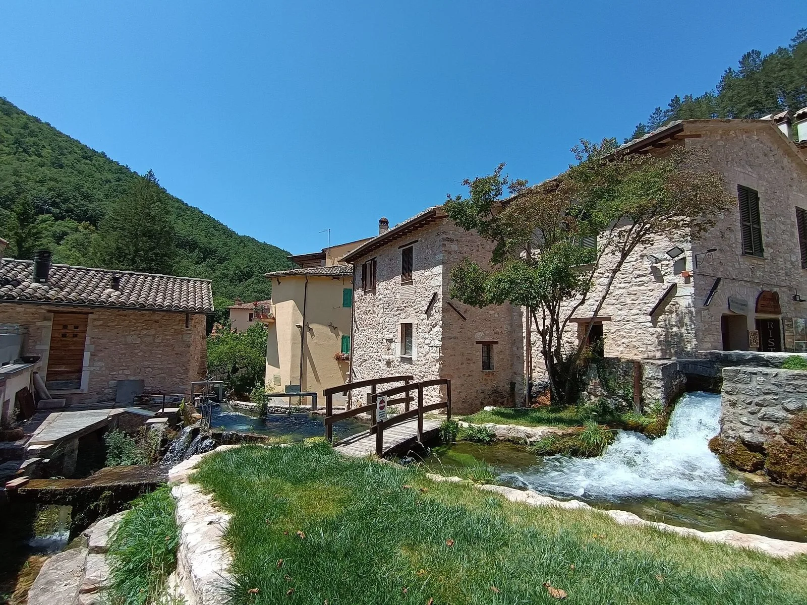 Ponticello in legno su una cascatella tra le case in pietra di Rasiglia